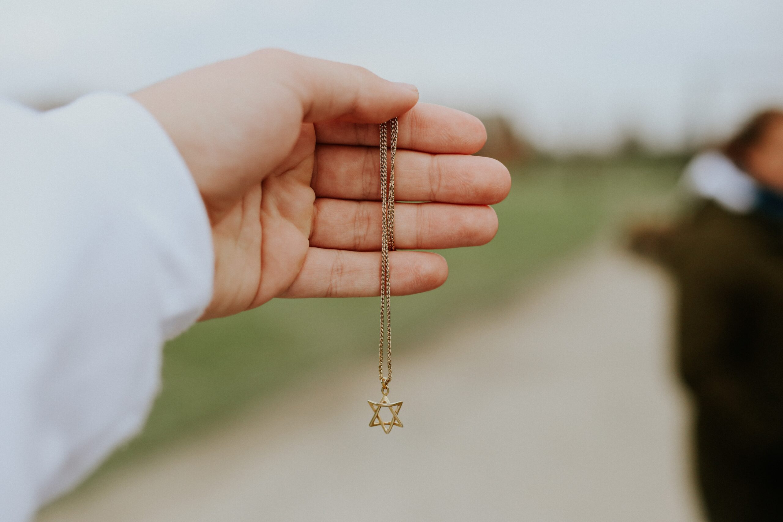 a hand holds a chain with a Star of David