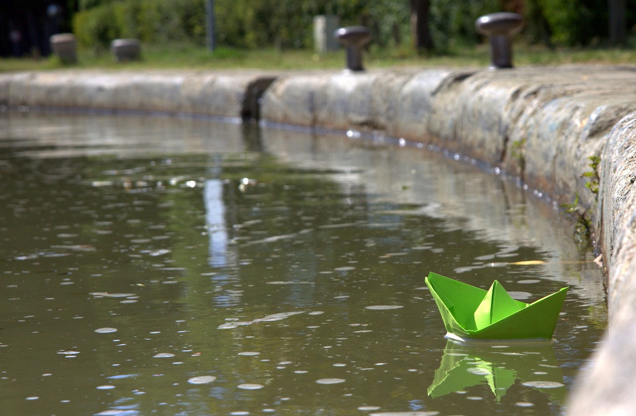 a paper boat sails on a pond