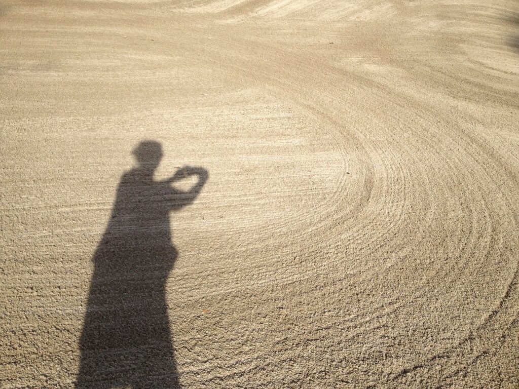 a woman in shadow across the sand