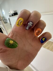 a hand showing five different nail colors with small designs