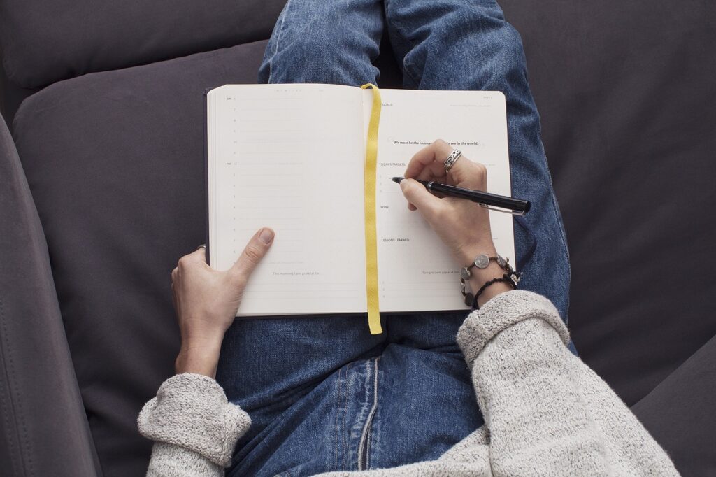 the hand of a woman writing in a journal