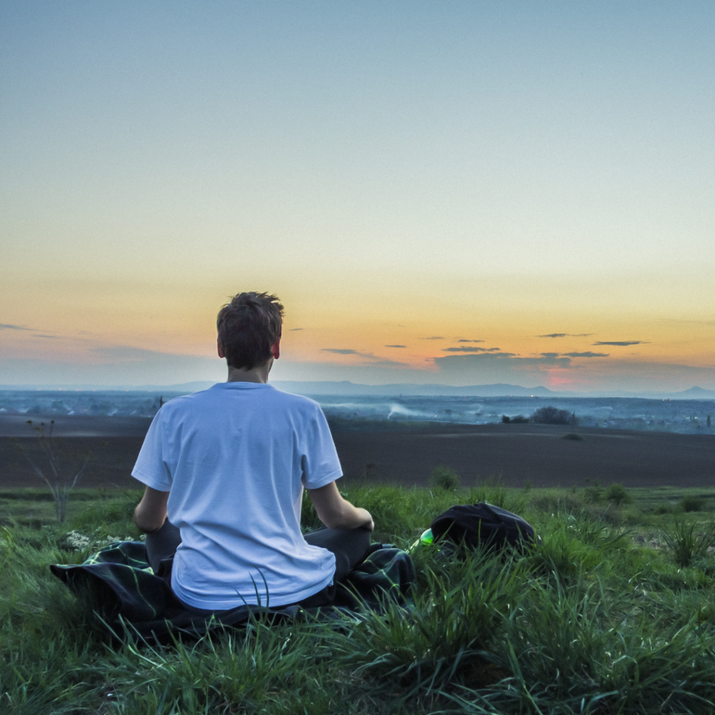 A person sitting on a mountain looking at a sunrise