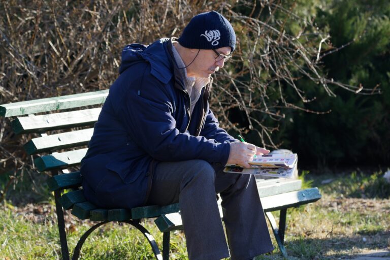 a man sitting on a bench doing a crossword puzzle
