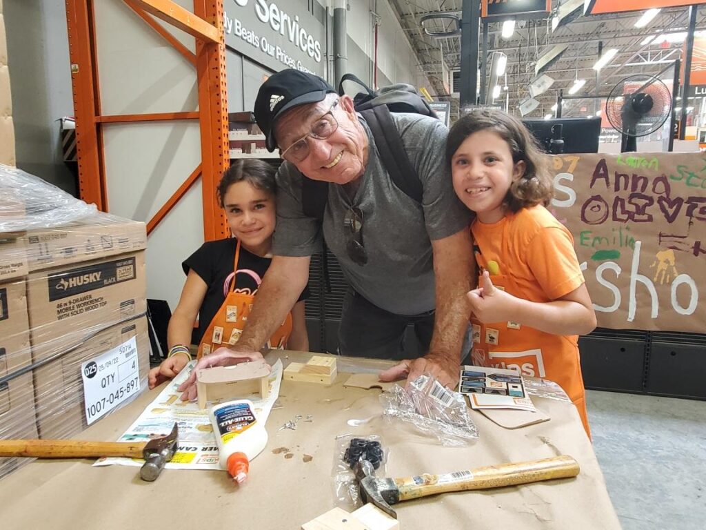 Robert stands in the middle of two granddaughters, tehy all smaile at the camera