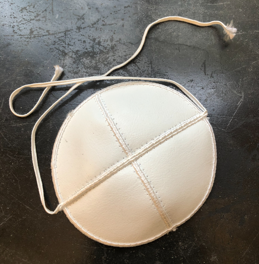 a small white kippah with white strings