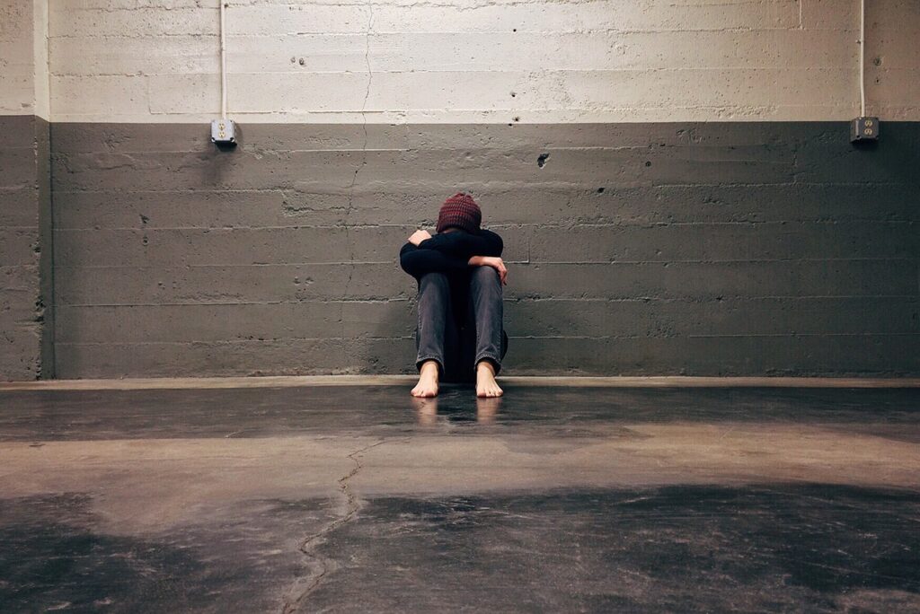 person sitting alone against a world head folded into their knees