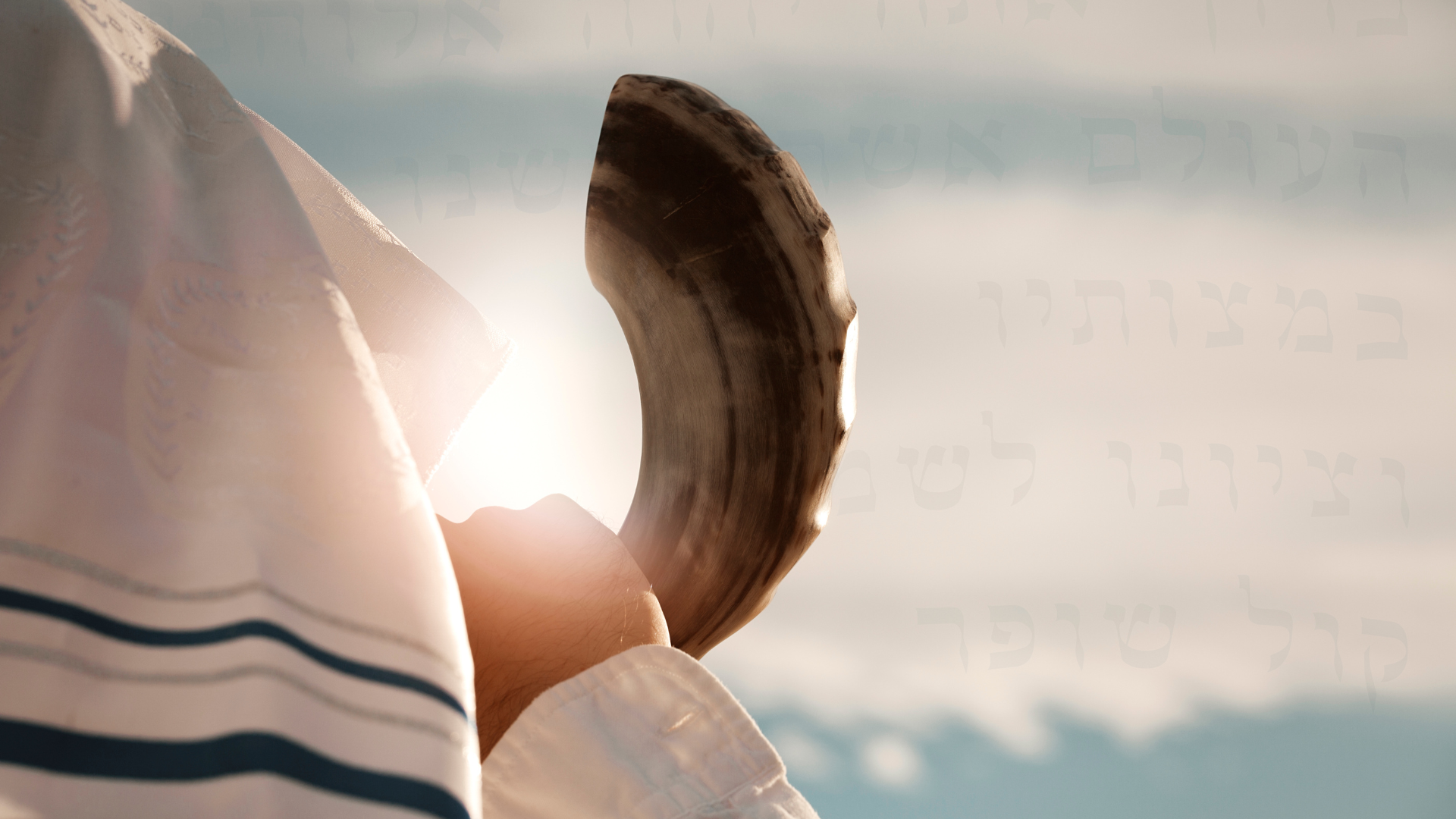 a person with a tallit over their head holds a shofar to their mouth