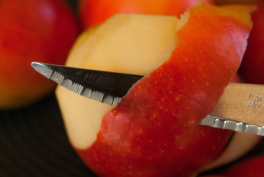 a knife slicing apple peel