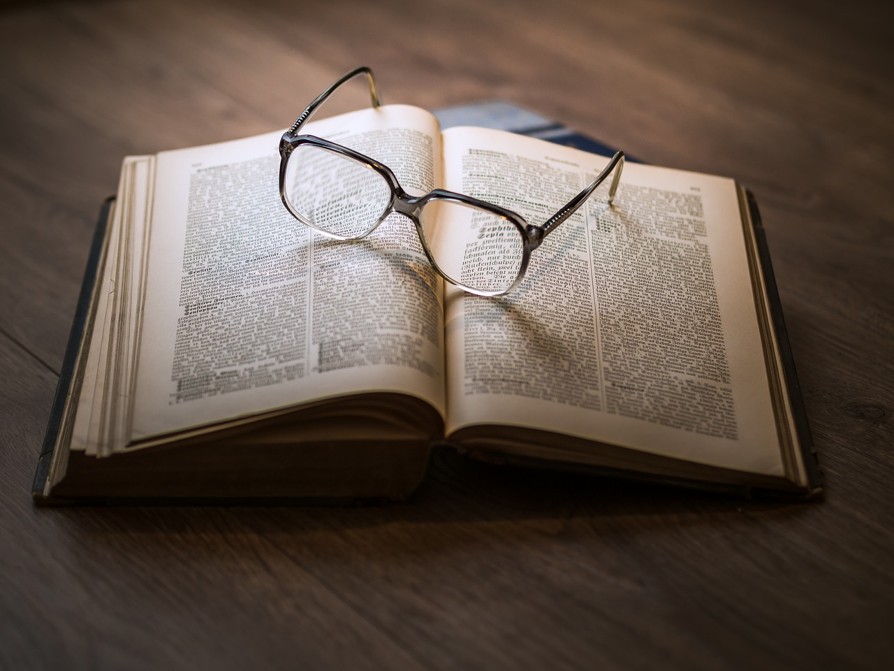 a pair of glasses sit on an open book