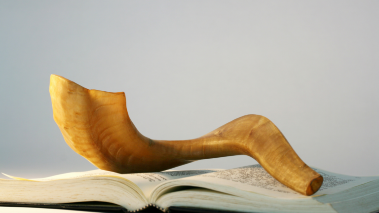 a brown shofar set on an open prayerbook