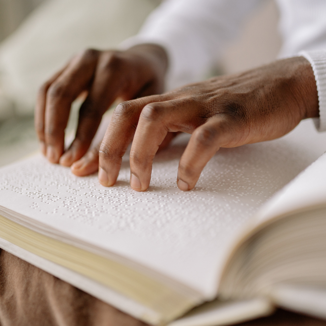 Hands reading Braille on an open book.