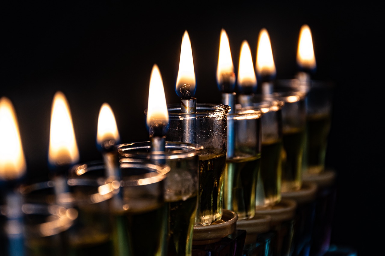 A row of lit candles in glass holders against a dark background.