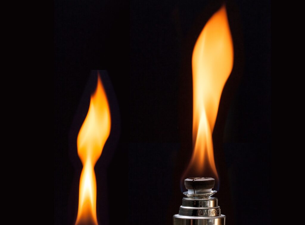 Close-up of a lighter with a tall, bright flame against a black background.