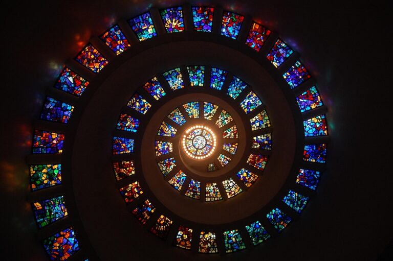 Spiral stained glass ceiling with colorful geometric patterns, viewed from directly below, forming a glowing center.