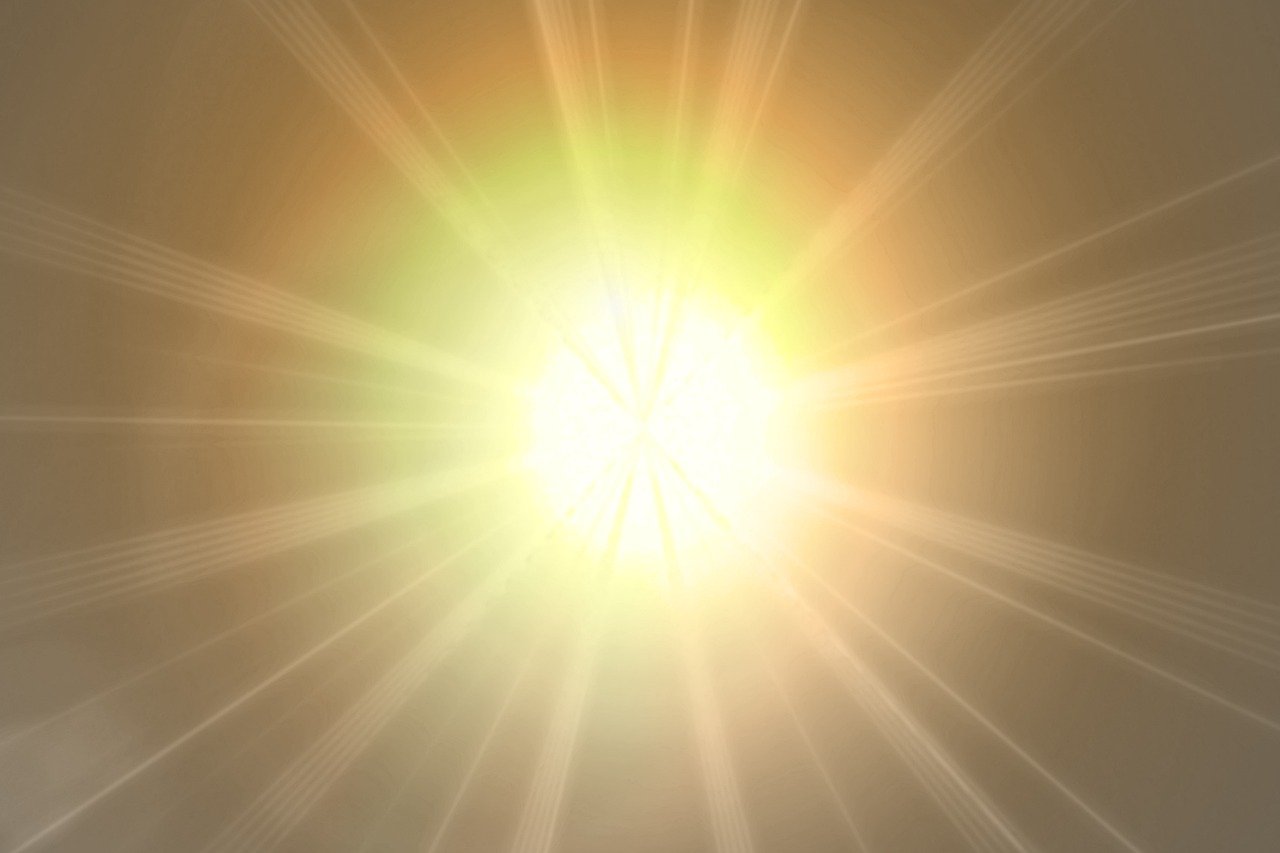 Bright yellow and orange sunburst with glowing rays radiating outward on a soft golden background.