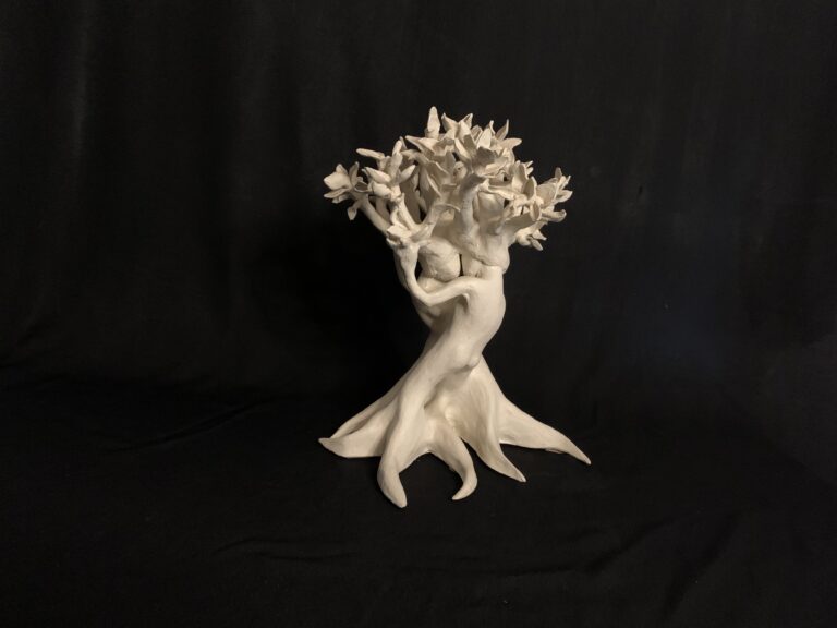 A white sculpture of two figures embracing, forming the trunk of a tree with branches at the top.