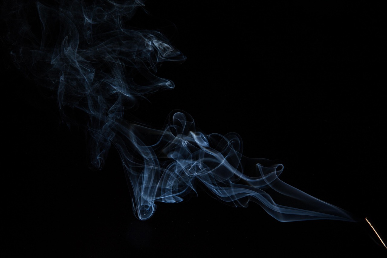 Wisps of blue smoke swirling against a black background, originating from the lower right corner.