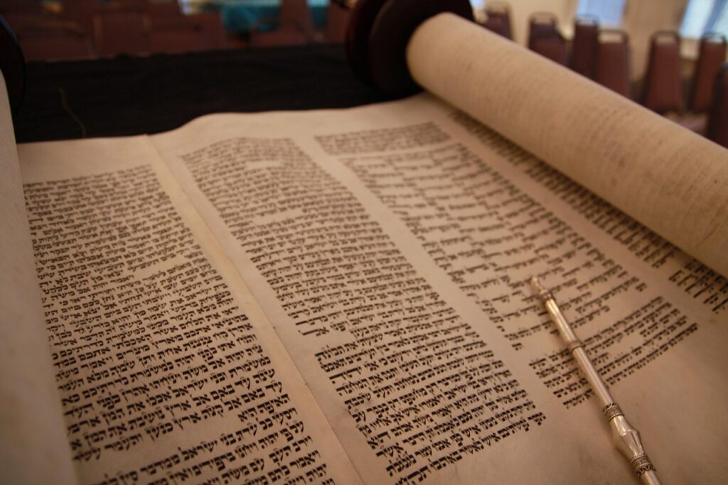 A Torah scroll with Hebrew text and a silver yad pointer resting on the parchment.