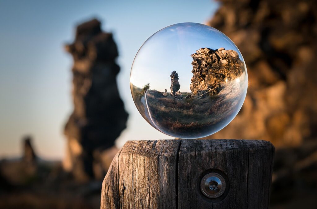 A rocky landscape is reflected upside down in a clear glass sphere on a weathered wooden post.