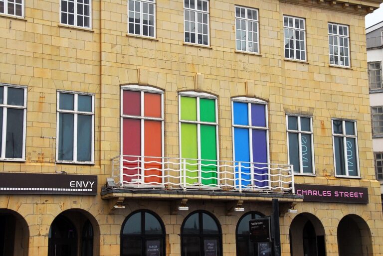 A building with tall windows in rainbow colors above shop signs reading ENVY and CHARLES STREET.