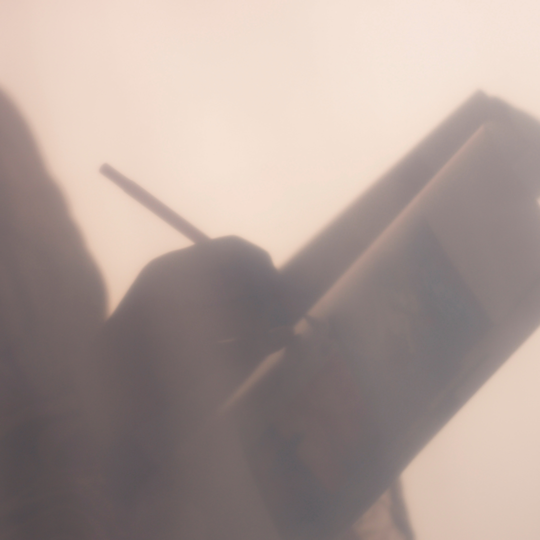 A blurred silhouette of a person writing or drawing in a notebook with a pencil.