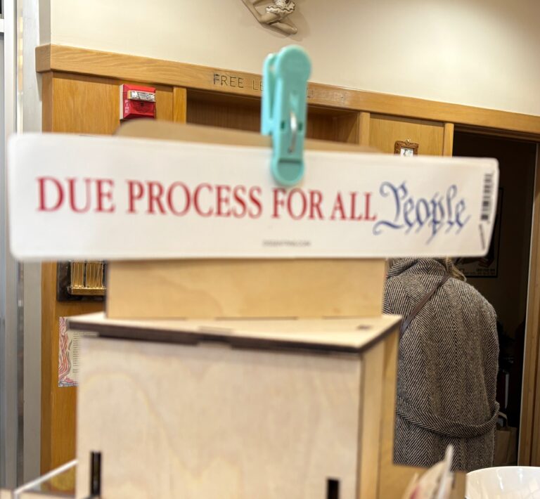 A sign clipped to a stand reads “DUE PROCESS FOR ALL People” in red and blue letters.