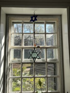 Two stained-glass Star of David ornaments hanging in a window.