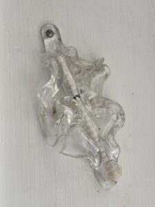 Clear, decorative glass finial screwed into a white wall.