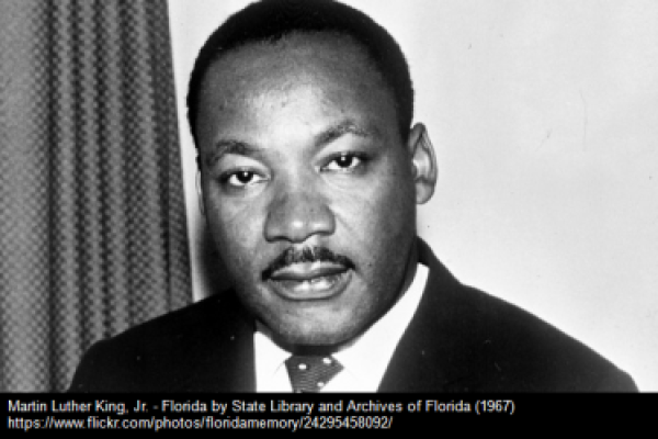 Black and white portrait of a man in a suit and tie, looking directly at the camera.