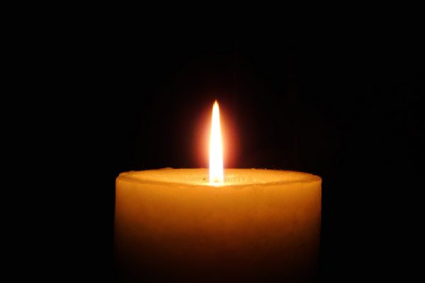 a lit candle glows against a dark background
