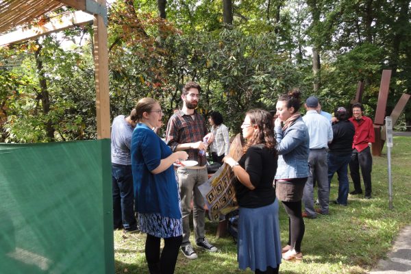 group of people standing around and chatting outside a sukkah