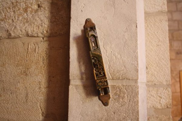 A decorative mezuzah is affixed to a stone wall.