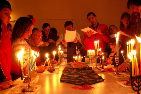 people gather to light multiple hanukkah menorahs