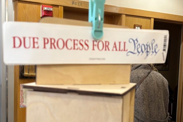 A sign clipped to a stand reads “DUE PROCESS FOR ALL People” in red and blue letters.