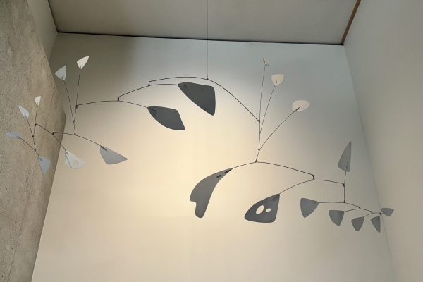 A hanging kinetic mobile featuring thin wire branches and abstract metal shapes suspended from the ceiling.