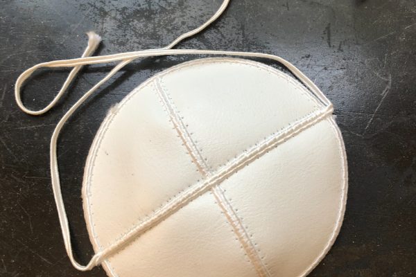 a small white kippah with white strings