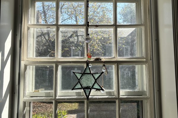 Two stained-glass Star of David ornaments hanging in a window.