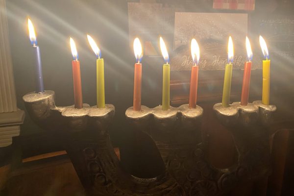 A lit menorah with nine candles, glowing brightly for Hanukkah on a dark background.