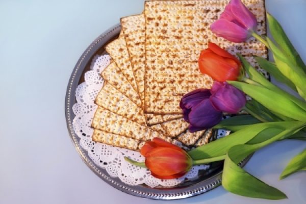 Matzo crackers on a silver tray with colorful tulips on the side.