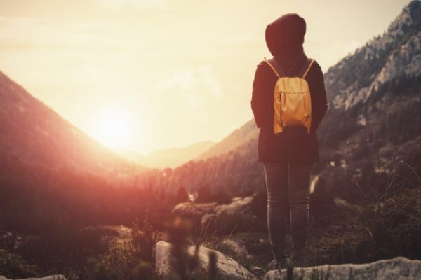 a hiker looks to the sunrise in the mountains