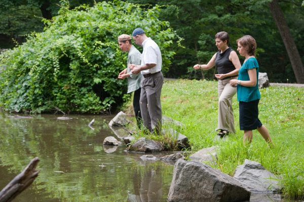 four people, two wearing kippot, stand at the edge of a body of water