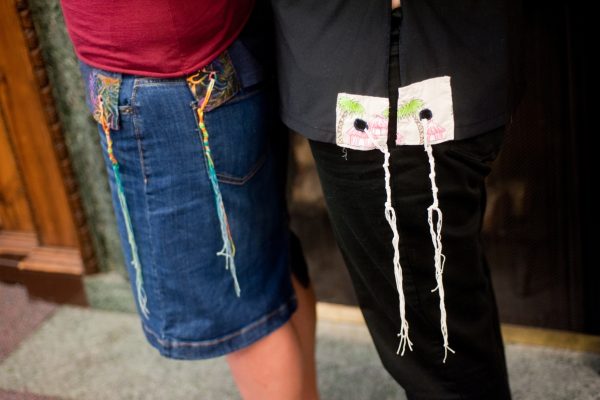 Two people standing side by side, each with strings hanging from their clothes.