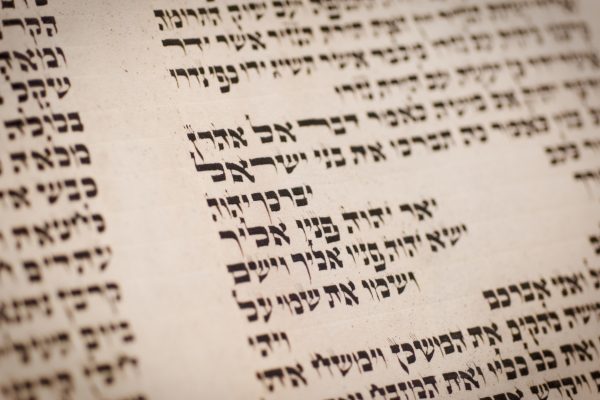 A close-up of a Hebrew text with large, bold characters on a scroll, showcasing traditional calligraphy.
