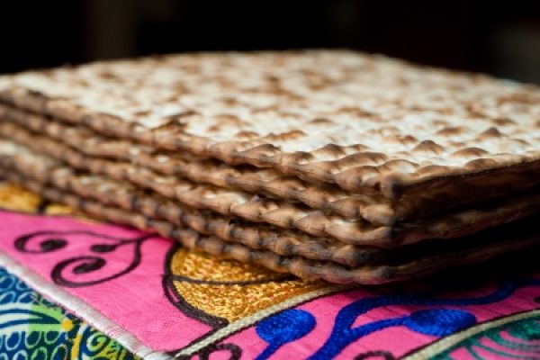 Stack of matzah on vibrant, colorful fabric with pink and blue patterns.