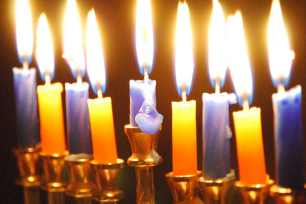 A menorah with nine lit candles, glowing against a dark background.