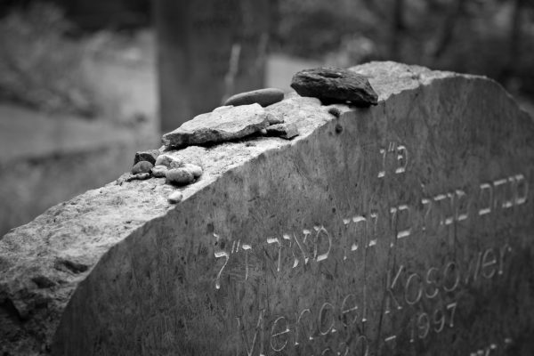 headstone with hebrew writing and stones on top