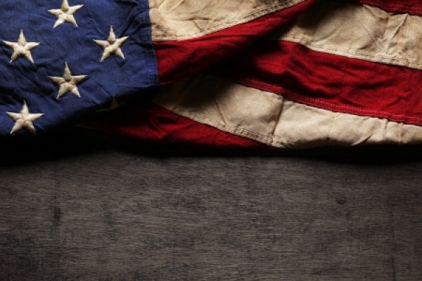 The American flag with stars and stripes partly folded on a dark textured surface.