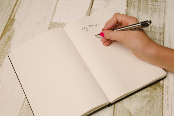 a hand writes "My Plan" in a blank journal