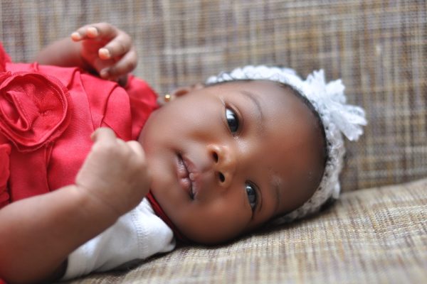 baby girl in white headband and red dress