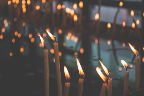 Lit candles with soft flames, reflecting light in a dimly lit room, creating a serene and calming atmosphere.